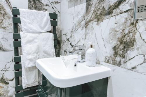 um lavatório branco numa casa de banho com paredes em mármore em Cosy 1Bed Apart with Wifi em Purley