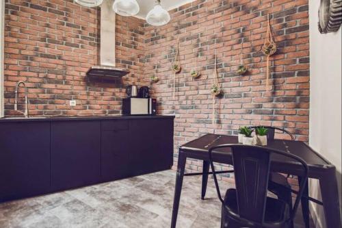 a kitchen with a table and a brick wall at Studio Cosy Tout Confort Porte Orléans 2 Pers Paris in Montrouge