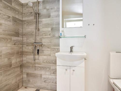 ein Badezimmer mit einem weißen Waschbecken und einer Dusche in der Unterkunft Holiday home Nexø XLI in Neksø