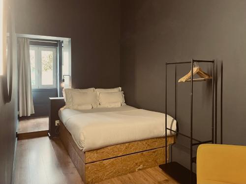 a small bedroom with a bed with white sheets at Avenue Hostel & Suites in Lisbon