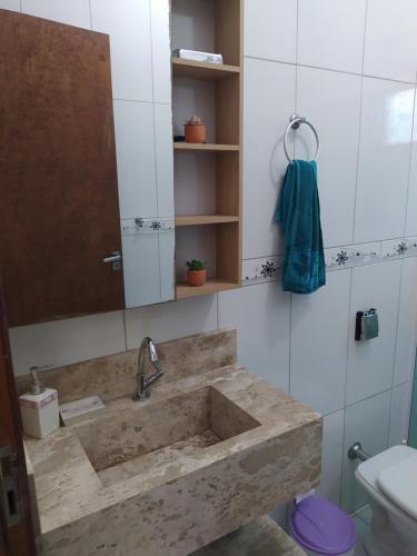 a bathroom with a sink and a mirror and a toilet at Imóvel com 02 quartos próxima ao Morro do Macaco in Bombinhas