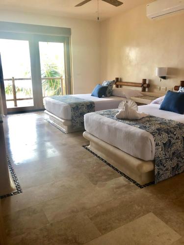 1 Schlafzimmer mit 3 Betten und einem großen Fenster in der Unterkunft New Beachfront Villa in Playa Blanca in Zihuatanejo