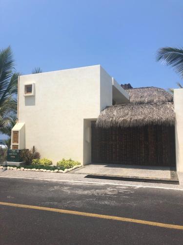 ein Gebäude mit einem Strohdach an der Straßenseite in der Unterkunft New Beachfront Villa in Playa Blanca in Zihuatanejo