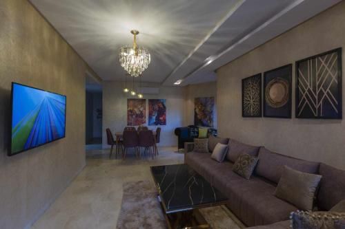 a living room with a couch and a television on a wall at Prestigia golf city porte agate in Marrakech