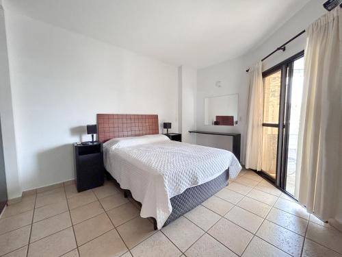a bedroom with a bed and a large window at Apartamento no Mercure - canal 3 in Santos
