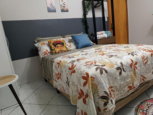 a bedroom with a bed with a floral comforter at Apezinho 209 in São Leopoldo