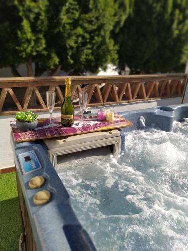 Villa Calida في كوين: حوض استحمام ساخن مع زجاجة من النبيذ وكؤوس