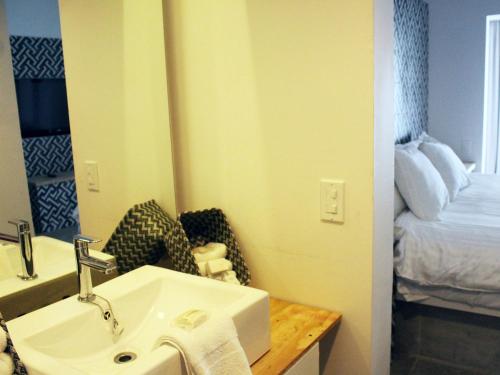 a bathroom with a sink and a mirror and a bed at Castillos Del Mar in Rosarito