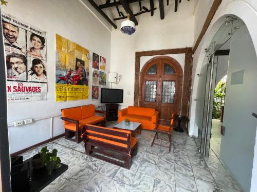 una sala de estar con muebles de color naranja y carteles en la pared en HOSTAL CHONTADURO Casa colonial en pleno centro histórico de Cali- Se alquila la casa entera para 12 o 13 personas o por habitaciones, en Cali