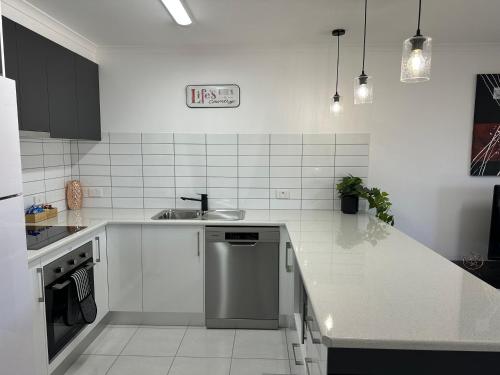 a white kitchen with a sink and a dishwasher at Allure Apartments - Central in Mildura