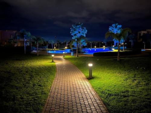 a brick pathway with lights in a park at night at Prestigia golf city porte agate in Marrakech