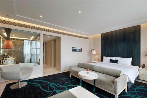 Hilton Xi'an High-tech Zone في شيان: غرفه فندقيه بسرير واريكه