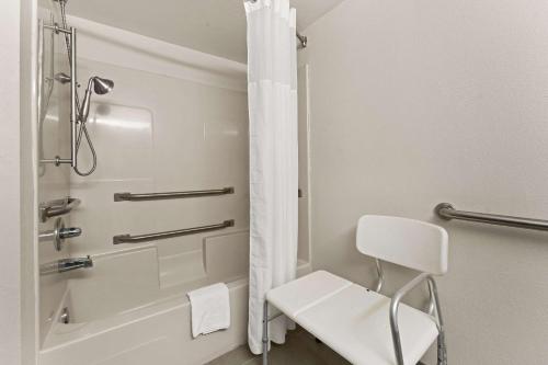 La salle de bains est pourvue d'une douche et d'une chaise blanche. dans l'établissement Quality Inn Sandersville, à Sandersville