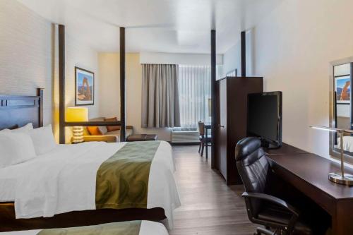 een hotelkamer met een bed en een flatscreen-tv bij Quality Suites Moab near Arches National Park in Moab