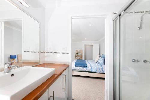 een badkamer met een wastafel en een slaapkamer met een bed bij Wallis Lake Retreat-Between the ocean and the lake in Tiona