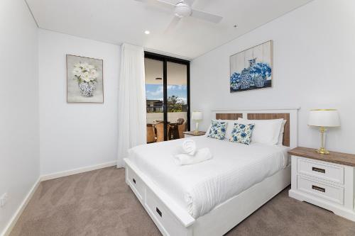 a white bedroom with a large bed and a window at Solaris 310 in Forster