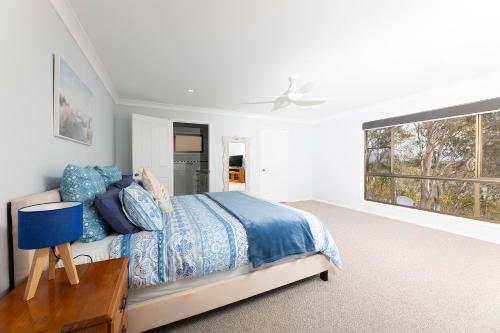 een witte slaapkamer met een bed en een raam bij Wallis Lake Retreat-Between the ocean and the lake in Tiona