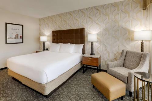 Drury Plaza Hotel Columbus Downtown في كولومبوس: غرفة نوم بسرير ابيض كبير وكرسي