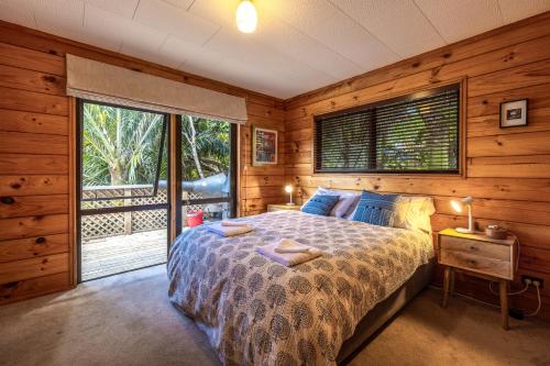 a bedroom with a bed and a large window at Onetangi Bliss - Waiheke Island Holiday Home in Onetangi