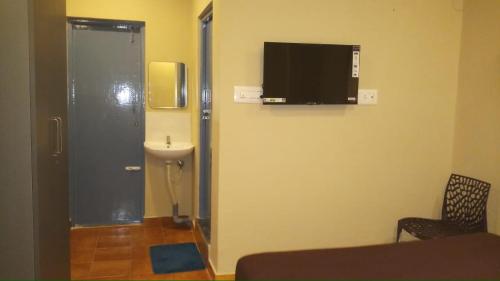 a bathroom with a sink and a television on the wall at The Nisarga Residency in Bangalore
