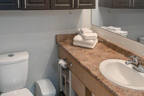 a bathroom with a toilet and a sink with towels at The Lepard's Den - Whitefoot Lodge 206 in Big White
