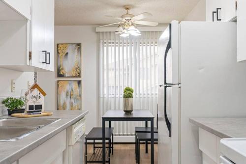 a kitchen with a refrigerator and a table with chairs at COZY 1BR Top Floor with Balcony Newly Renovated in Fort McMurray