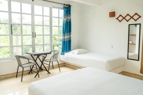 a bedroom with two beds and a table and chairs at Casa Mazunte Tierra Viva in Mazunte