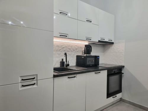 una cucina con armadietti bianchi e forno a microonde di Apartament przy Świebodzkim a Breslavia