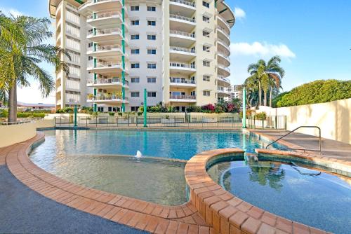 a swimming pool in front of a large building at Harbour Haven - A Parkside CBD Address in Darwin