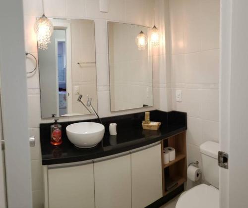 La salle de bains est pourvue d'un lavabo, d'un miroir et de toilettes. dans l'établissement Apartamento na Praia Brava - Florianópolis, à Florianópolis