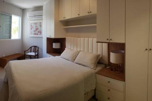 - une chambre avec un grand lit blanc et un bureau dans l'établissement Apartamento na Praia Brava - Florianópolis, à Florianópolis