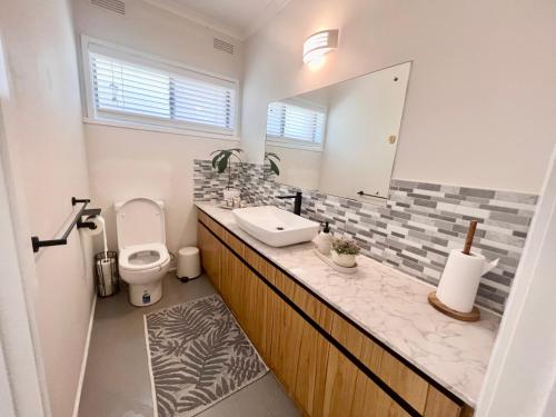 a bathroom with a sink and a toilet and a mirror at Cozy and nice stay with sunset view! in Mooroolbark