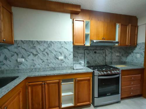a kitchen with wooden cabinets and a stove top oven at Elegante Suite ecualodge2 in Cuenca