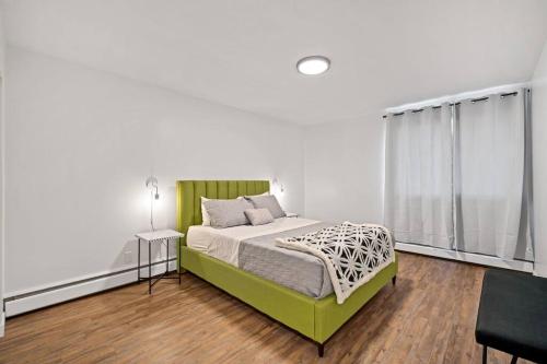 ein Schlafzimmer mit einem grünen Bett und einem Fenster in der Unterkunft Spacious 2BR Top Floor with Balcony Free WiFi in Fort McMurray