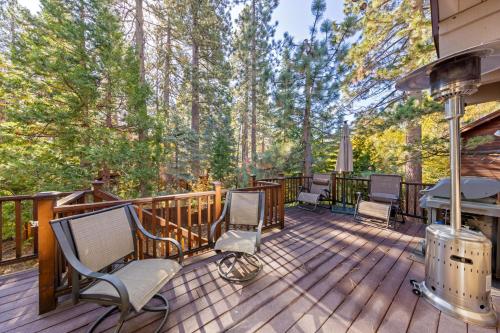 a deck with chairs and a grill and trees at Nightingale Retreat by Tahoe Getaways - 3BR, Close to Tahoe City, Walk to Bike Path & Private Beach Access in Tahoe City