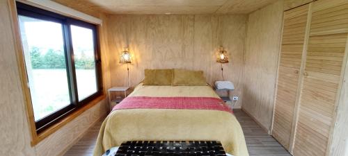 1 dormitorio con 1 cama en una habitación con 2 ventanas en Casa Rayen Puerto Varas, en Puerto Varas