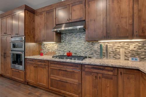 a kitchen with wooden cabinets and a stove top oven at Truckee Luxe by Tahoe Getaways - 3 BR Luxury Gray's Crossing Townhome w Hot Tub on Golf Course - Close to Downtown & Northstar in Truckee
