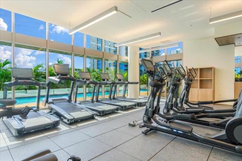 une salle de sport avec une rangée de tapis de course et une piscine dans l'établissement Sky Ala Moana 2908 condo, à Honolulu