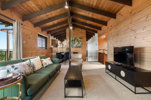 a living room with a green couch and a flat screen tv at Sunset Lodge - Breathtaking Views in Orange
