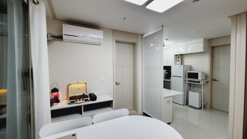 una pequeña cocina blanca con sillas blancas y nevera. en Full option two-room mountain view private house I en Seúl