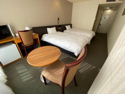 a hotel room with two beds and a table and chairs at Hotel Continental Fuchu in Fuchu