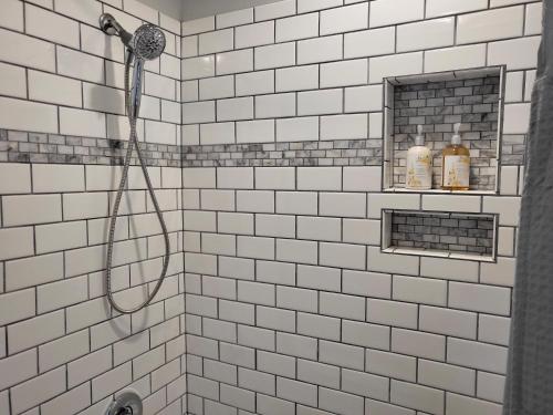 a white tiled shower with a hose in a bathroom at Private space, while visiting family this Holiday! in Pottstown