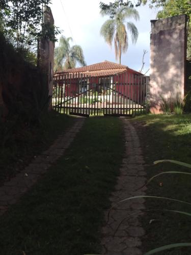 una cerca frente a una casa con una palmera en Chácara pão de açúcar, en Bueno Brandão