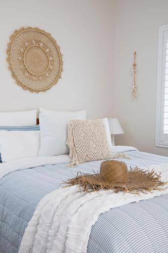 a bedroom with a bed with a straw hat on it at Kalinda in Mollymook