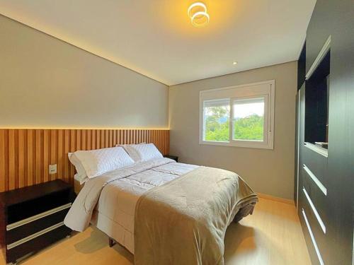 ein Schlafzimmer mit einem großen Bett und einem Fenster in der Unterkunft Apartamento em Gramado - Valle Montano in Gramado