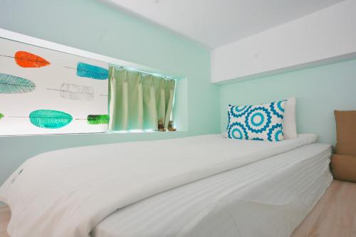 a bedroom with a white bed and a window at 日日旅樹 Green Stay in Hualien City