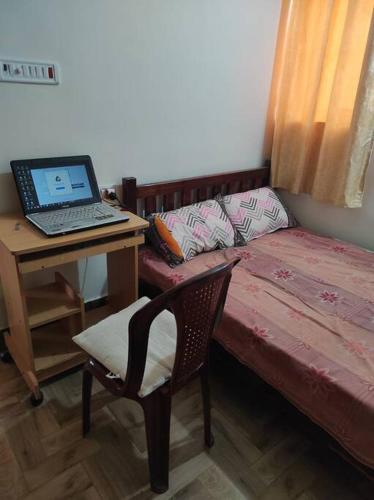 a room with a bed and a desk with a laptop at Muktamma in Tiruvannāmalai