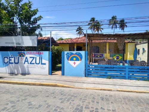 a blue fence with a sign on the side of a street at POUSADA CÉU AZUL in Porto De Galinhas