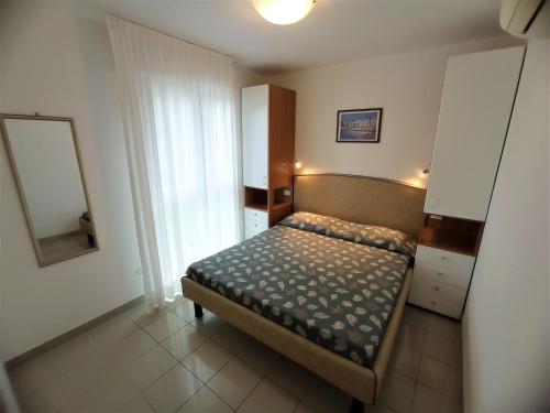 ein kleines Schlafzimmer mit einem Bett und einem Spiegel in der Unterkunft Relax in the terrace of our flat - Beahost in Lignano Sabbiadoro