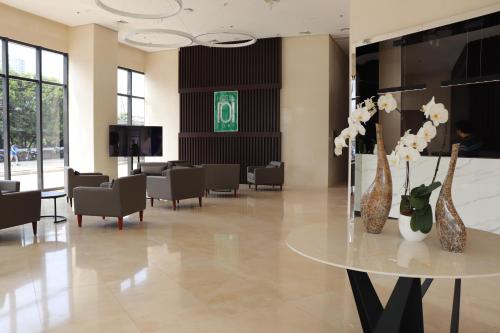 un vestíbulo con una mesa con flores y sillas en Hotel101 - Fort, en Manila